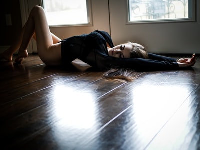 身穿黑色长袖连体衣的女子躺在门旁的地上